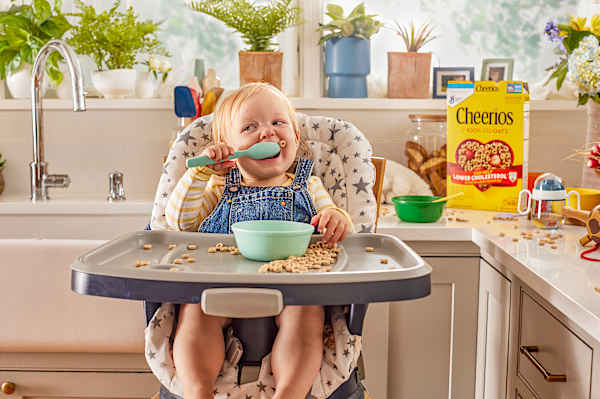 Young child in high chair eating a bowl of Cheerios